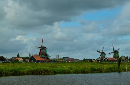 Zaanse Schans, Holland, August 2019. North-east of Amsterdam is a small community located on the quay of the Zaan river. View from above of the fields with mills, tourists are noticed. Cloudy day.のeditorial素材