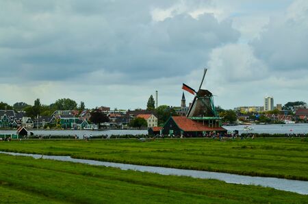 Zaanse Schans, Holland, August 2019. North-east of Amsterdam is a small community located on the quay of the Zaan river. View from above of the fields with mills, tourists are noticed. Cloudy day.のeditorial素材