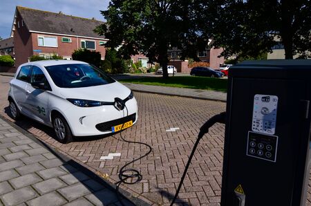Edam, the Netherlands, August 2019. A Renault Zoe connected to the electric charging station. The charging socket is on the face of the machine. On the side a writing that it is an electric model.のeditorial素材