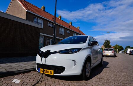 Edam, the Netherlands, August 2019. A Renault Zoe connected to the electric charging station. The charging socket is on the face of the machine. On the side a writing that it is an electric model.のeditorial素材
