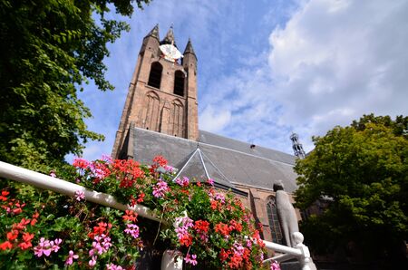 Delft, Holland, August 2019. The bell tower of the old church, the Oude Kerk, stands out imposingly over the city. Planters give color to the image.のeditorial素材