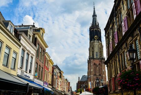 Delft, the Netherlands, August 2019. The bell tower of the new church, in Dutch Nieuwe Kerk. Characterized by red bricks, with its height and grandeur it stands out immediately. Blue sky, white cloudsのeditorial素材