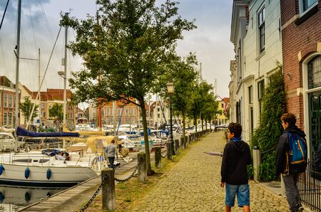 Goes, the netherlands, august 2019. View of the small and pretty harbor. It creeps between the historic houses of the center, along the piers trees and lampposts with planters.のeditorial素材