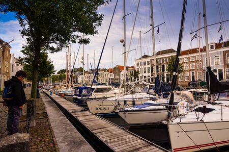 Goes, the netherlands, august 2019. View of the small and pretty harbor. It creeps between the historic houses of the center, along the piers trees and lampposts with planters.のeditorial素材