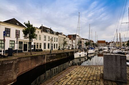 Goes, the netherlands, august 2019. View of the small and pretty harbor. It creeps between the historic houses of the center, along the piers trees and lampposts with planters.のeditorial素材