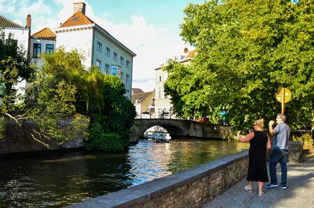 Bruges, Belgium. August 2019. One of the ancient stone bridges: they characterize the place with their medieval charm. A pair of passersby stopped to watch.のeditorial素材