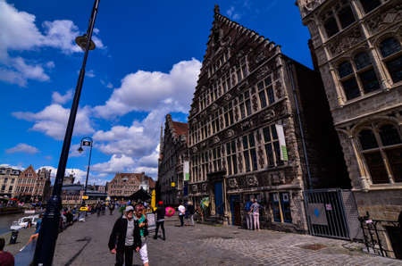 Ghent, Belgium, August 2019. The Korenlei is a historical landmark: the most beautiful buildings overlook the canal. People walk along the bank, some sit to watch the boats go by.のeditorial素材