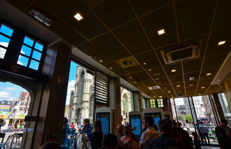 Ghent, Belgium, August 2019. Particular point of view for the St. Nicholas church. We are inside the mcdonald, recognizable on the big screens for ordering. Customers.のeditorial素材