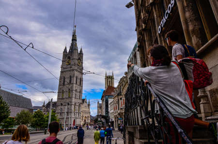 Ghent, Belgium, August 2019. The bell tower called Beffroi behind the church of St. Nicholas. A tourist with her boys points to it.のeditorial素材