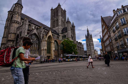 Ghent, Belgium, August 2019. Two boys consult the tourist map, behind them we recognize the church of St. Nicholas and the bell tower, the Beffroi.のeditorial素材