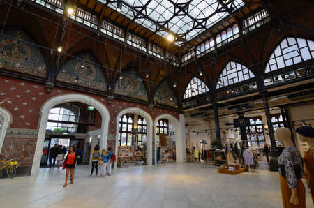 Ghent, Belgium, August 2019. The Post is a boutique hotel based in the former post office, an emblematic historical building in the center. People walk in the large living room indoors. Glazed canopy.のeditorial素材