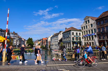 Ghent, Belgium, August 2019. Pleasant view of one of the canals in the historic center. The floristas color the railings of the bridge, people walk along it. Sunny day with blue sky and white clouds.のeditorial素材
