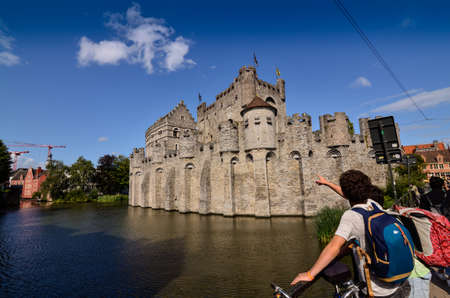 Ghent, Belgium, August 2019. The Gravensteen is the castle of the counts of Flanders. View from the side of the moat: the imposing medieval structure attracts the attention of the people. Sunny day.のeditorial素材