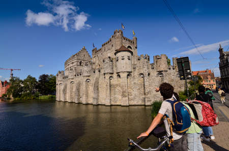 Ghent, Belgium, August 2019. The Gravensteen is the castle of the counts of Flanders. View from the side of the moat: the imposing medieval structure attracts the attention of the people. Sunny day.のeditorial素材