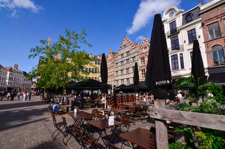 Ghent, Belgium. August 2019. On the historical square of the center, the Korenmarkt, there are bars and restaurants with tables and umbrellas on the street. People at the tables and walking.のeditorial素材