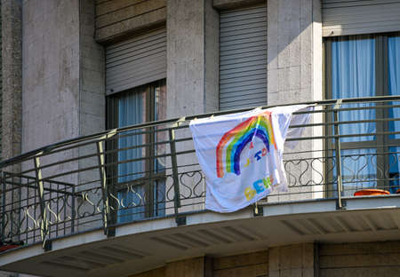 Turin, Piedmont,Italy. April 2020. Coronavirus. The sheets of the rainbow hang on the facades of the houses give message "everything will be fine" in italian "tutto andrÃ¨ bene".The Italian flag besideのeditorial素材