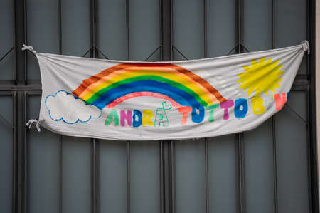 Turin, Piedmont, Italy. May 2020. Coronavirus pandemic. On the facades of the houses hang the sheets with the drawing of the rainbow and message everything will be fine. In Italian "AndrÃ  tutto bene"のeditorial素材