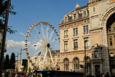 Antwerp, Flanders, Belgium. August 2019. The entrance facade of the imposing railway station. On the left a ferris wheel. Blue sky with white clouds.のeditorial素材
