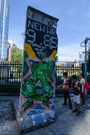 Brussels, Belgium, August 2019. A slice of the Berlin Wall at the entrance to the parliamentary offices. Some tourists are watching it.のeditorial素材