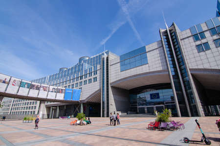Brussels, Belgium, August 2019. External view of the modern metal and glass palaces which house the European Parliament. Entrance dedicated to Altiero Spinelli: tourists take souvenir photos.のeditorial素材