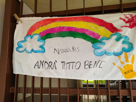 Turin, Piedmont, Italy. June 2020. Coronavirus pandemic. On the facades of the houses hang the sheets with the drawing of the rainbow and message everything will be fine. In Italian "AndrÃ  tutto bene"のeditorial素材