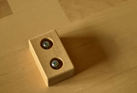 Close-up shot of a pair of screws that is fixed with an electric screwdriver on a light wooden board.のeditorial素材