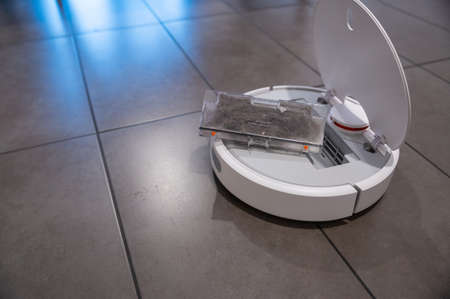 House scenes: house cleaning, the robot vacuum cleaner has a tank full of dirt: it has been...