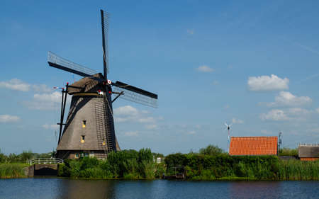 Kinderdijk, The Netherlands, August 2019. On a beautiful summer day a historic windmill, in perfect condition, in the Dutch countryside furrowed by canals lined with tall green grasses.の写真素材