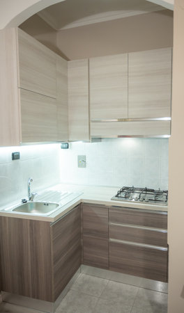 View of a modular corner kitchen in gray and brown color, the led under-cabinet light attracts attention.の写真素材