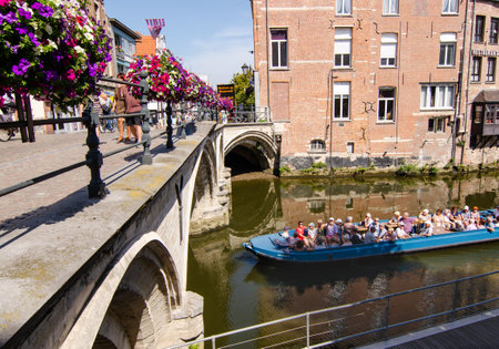 August 2019. In the historic center, the bridges are decorated with brightly colored flower boxes. A tourist boat is passing below.のeditorial素材