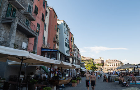 Portovenere, Liguria, Italy. June 2020. View of the promenade in front of the beautiful houses with colorful facades: people walking along seaside.のeditorial素材