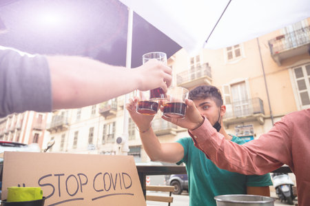 Three friends are toasting to an exit after the  virus lockdown. They have a sign that says stop...