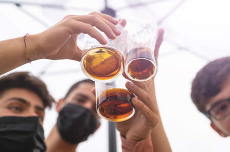 Three friends toast to the exit after the  lockdown. Close up shot on the bottom of the glasses. Concept of friendship, new normal, pandemic fight.の写真素材