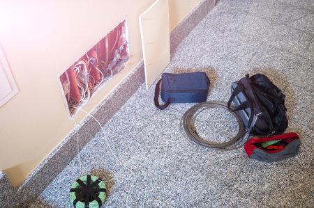 A junction box: it was opened to do some work. Next to the electrician's tools a probe passes cables, a skein of new wire, the bag.の写真素材