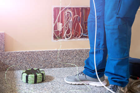 An electrician at work: he grabs new cables already threaded into a pipe and moves them to make it easier to slide inside.の写真素材