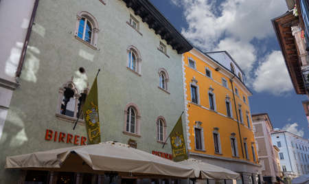 Trento, Italy, June 2021. The forst brewery is a reference in the city for drink lovers. The two flags on the facade of the house where it is based leave no doubt. Customers can be seen.のeditorial素材