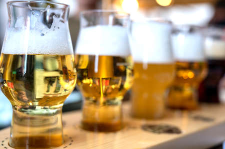 Brewery tasting with five glasses of different color and opacity of the drink. Blurred and indistinguishable background of the brewery.の写真素材