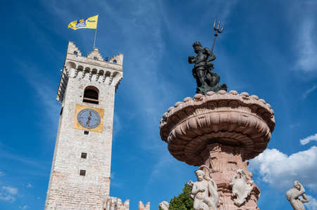 Trento, Italy, June 2021. Beautiful photo in the main square: detail of the fountain of Neptune with the civic tower in the background. Nice sunny day.のeditorial素材