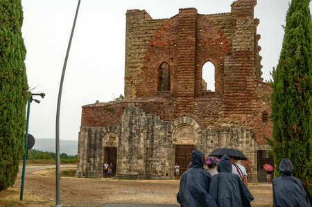 San Galgano, Chiusdino, Italy. August 2020. Conceptual image of meteorological variability: a group of tourists try to protect themselves from a summer storm with plastic capes.のeditorial素材