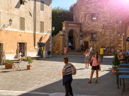 San Quirico d'Orcia, Tuscany, Italy. August 2020. People stroll after passing through one of the entrance doors in the walls of the village. Beautiful summer day.のeditorial素材