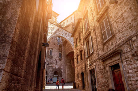 Perugia, Umbria, Italy. August 2020. In an alley in the historic center, an arch connects two tall medieval buildings. People.のeditorial素材