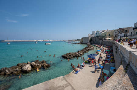 Otranto, Puglia, Italy. August 2021. Amazing view of the promenade, people enjoy the crystal clear sea while swimming. Beautiful summer day.の写真素材
