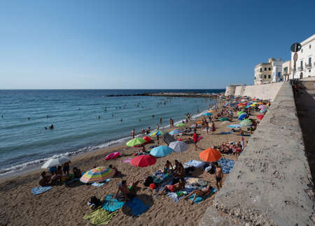 Gallipoli, Puglia, Italy. August 2021. The sandy beach in the old town is packed with people bathing and sunbathing.の写真素材