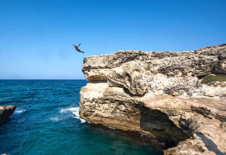 Roca Vecchia, Melendugno,Puglia Italy. August 2021. Footage of the Grotta della Poesia, an amazing natural pool connected to the open sea. People enjoy the heavenly place by diving. A man takes a dip.のeditorial素材