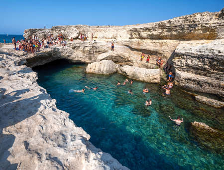 Roca Vecchia, Melendugno, Puglia Italy. August 2021. Footage of the Grotta della Poesia, an amazing natural pool connected to the open sea. People enjoy the heavenly place by diving.のeditorial素材