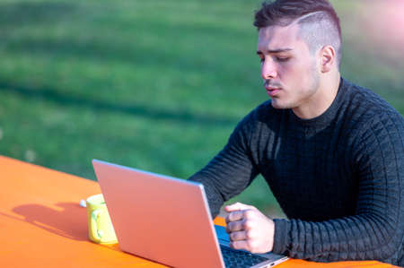 Portrait of attractive young office worker in casual wear, talking with colleague off camera. He...