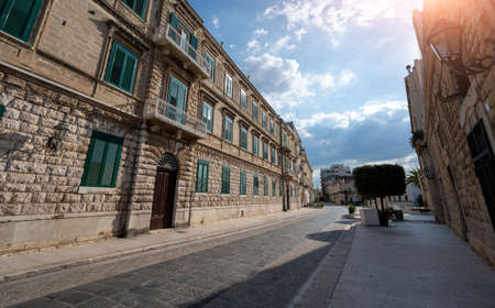 Trani, Puglia, Italy. August 2021. A charming street in the historic center overlooked by period houses with green windows. Beautiful summer day with blue sky and white clouds.のeditorial素材