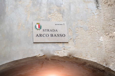 Bari, Puglia, Italy. August 2022. The plaque of the street called the low arch road, in Italian "low arch road": it is one of the access points to the historic village.の写真素材