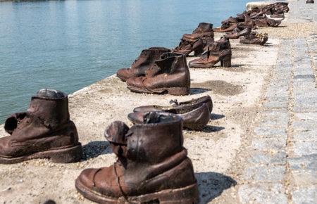 Budapest, Hungary. 25 August 2022. Memorial to the victims of the Nazi repression. Rusty metal copies of old shoes on the Danube River embankment. Holocaust and Nazi terror memory concept.の写真素材