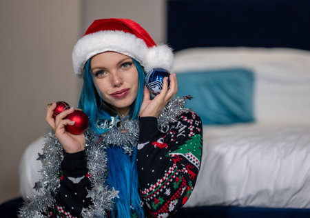 Portrait of a beautiful hipster Caucasian woman in Christmas clothes.She poses looking at the camera holding colorful balls and a silver decoration around her neck.Beauty,Christmas holidays,positivityの写真素材